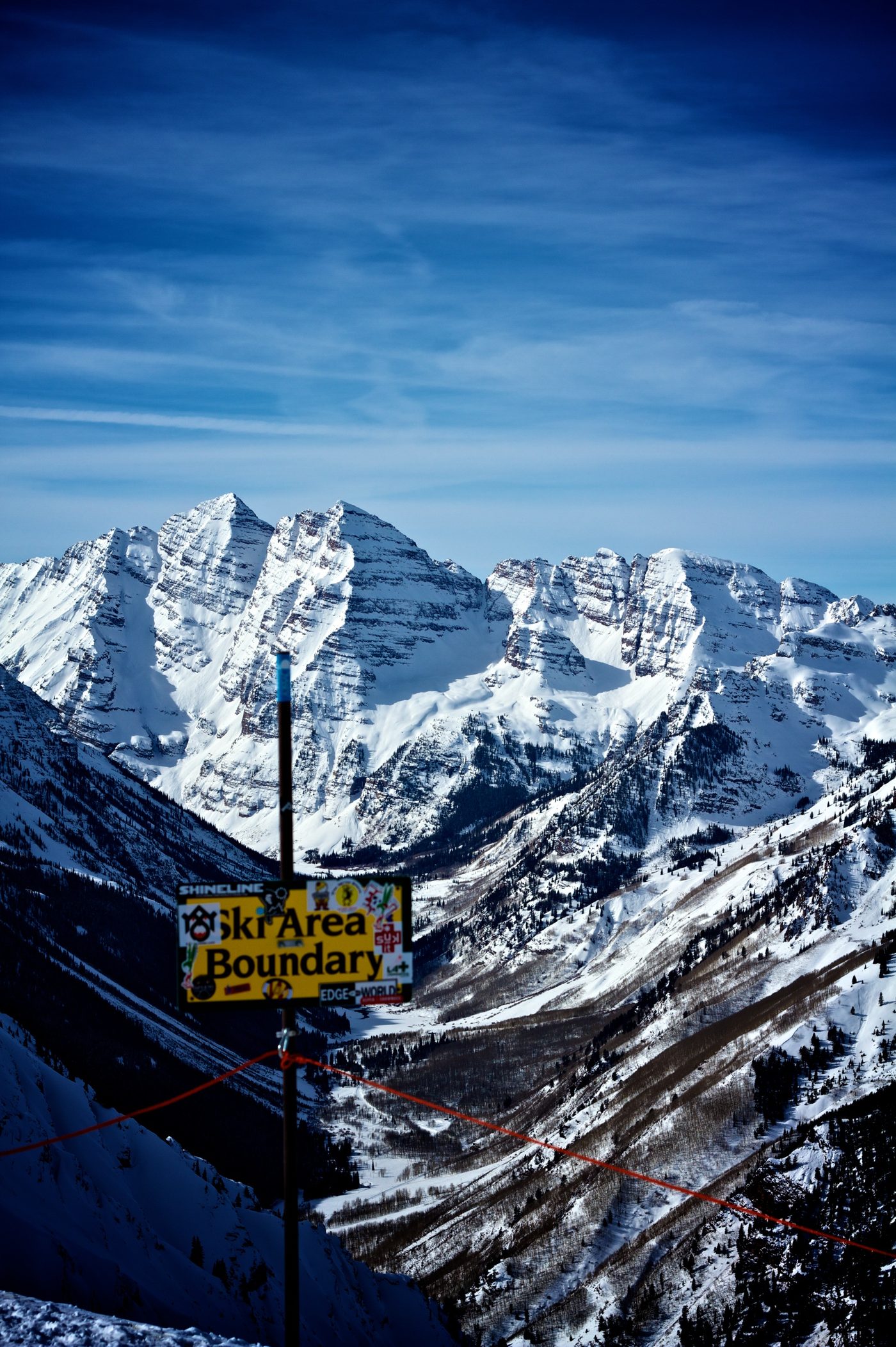 A yellow ski area boundary sign marking the edge of patrolled terrain near Aspen Highlands, Colorado