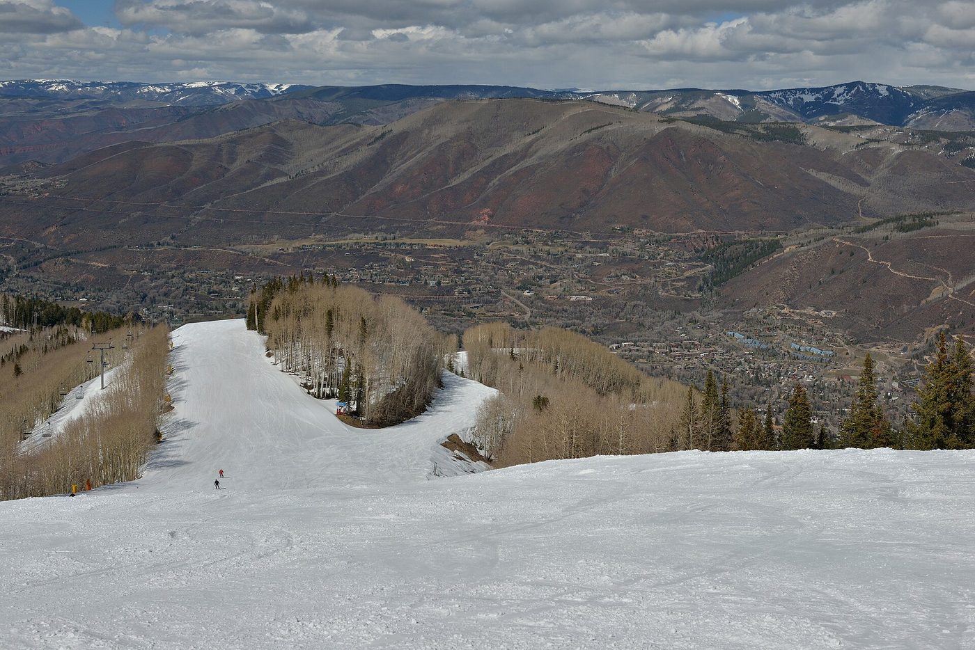 A skier descending Ruthie's Run on Aspen Mountain in spring, with the town of Aspen below