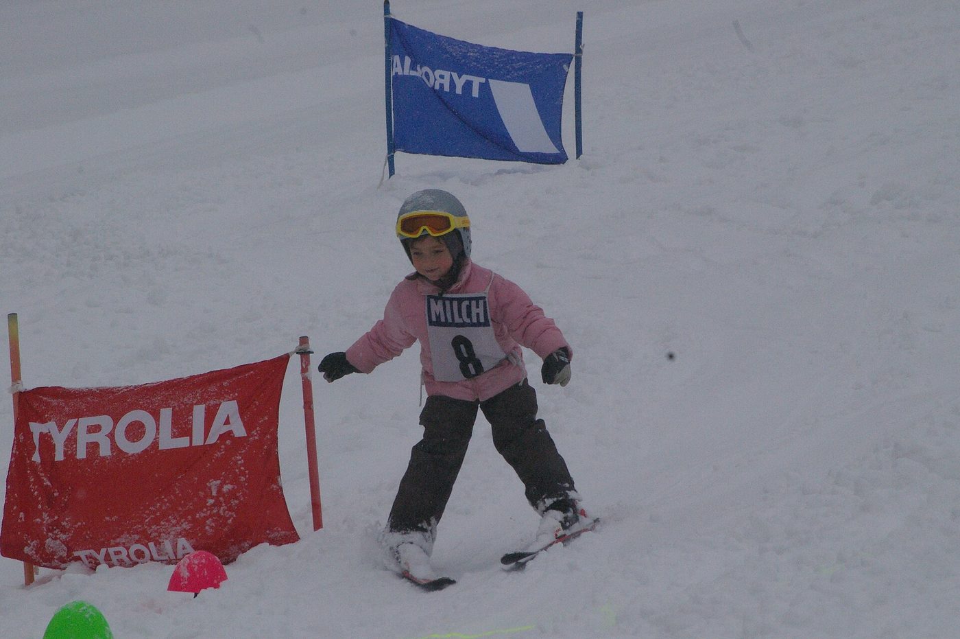A young child in a helmet skiing through gates on a ski school course
