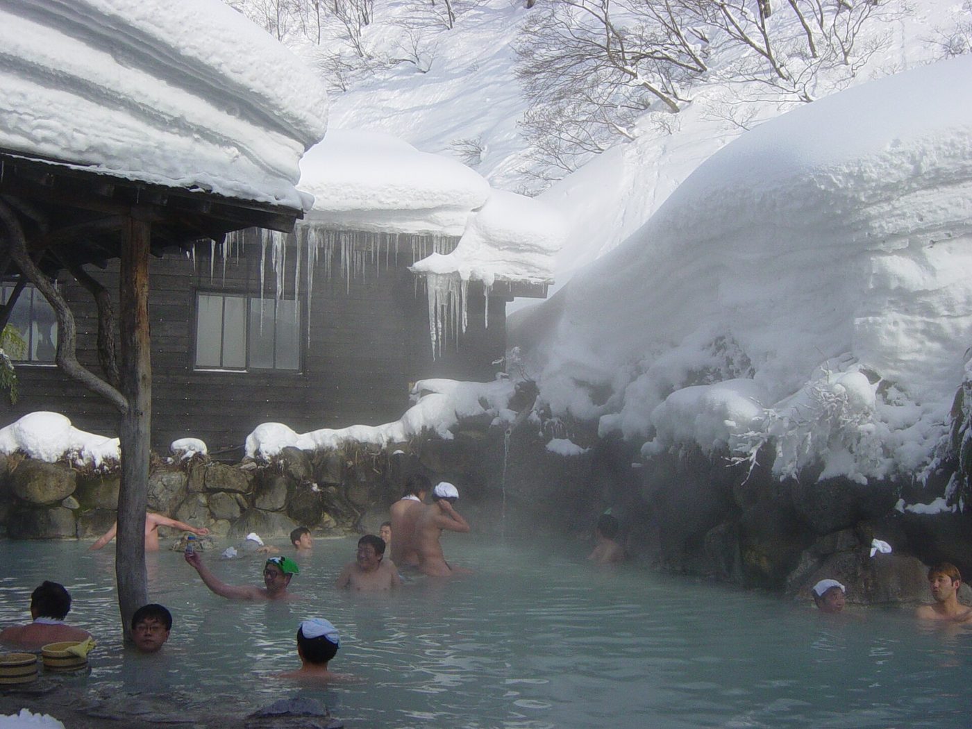 Bathers in a steaming outdoor onsen surrounded by deep snow