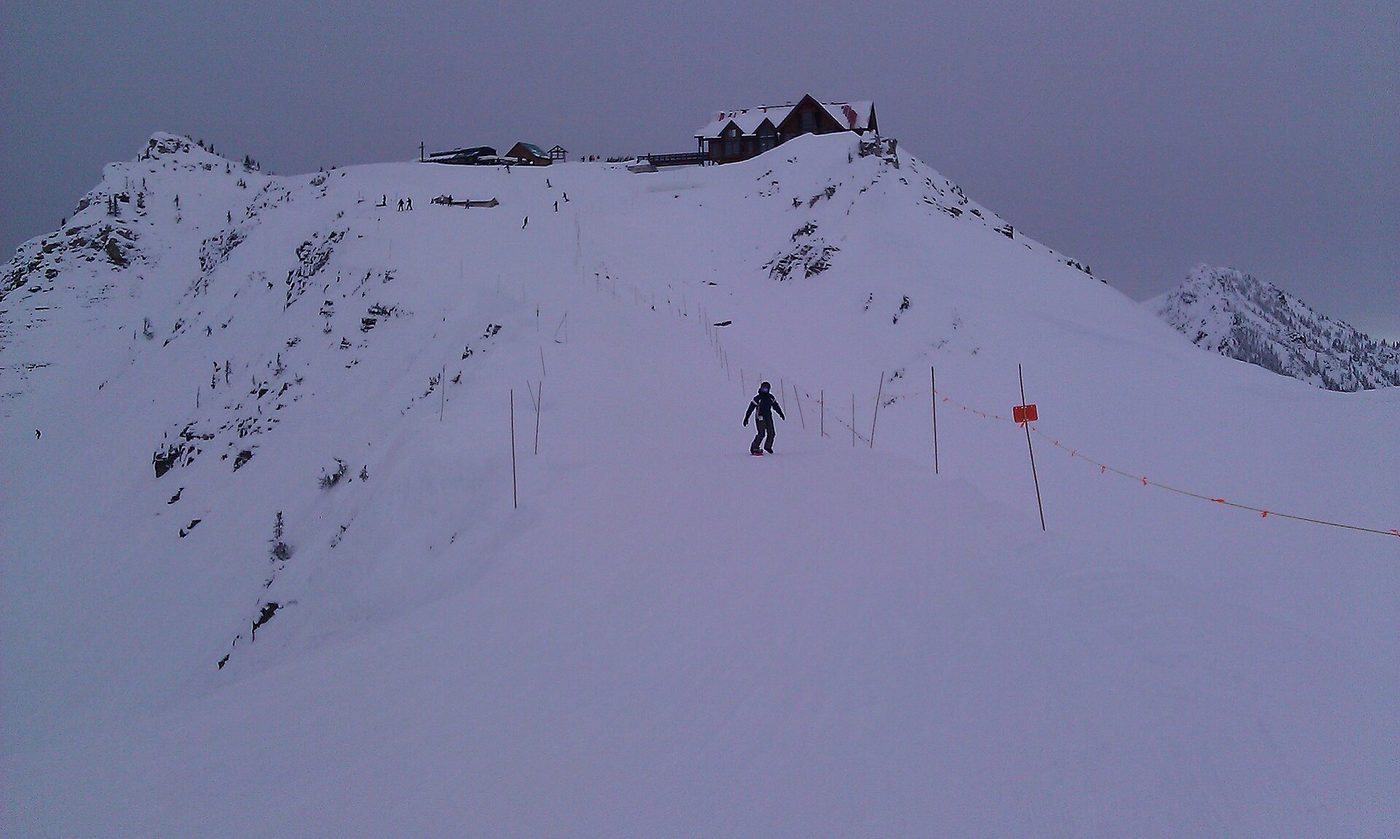 A lone snowboarder below the summit lodge at Kicking Horse Mountain Resort, British Columbia