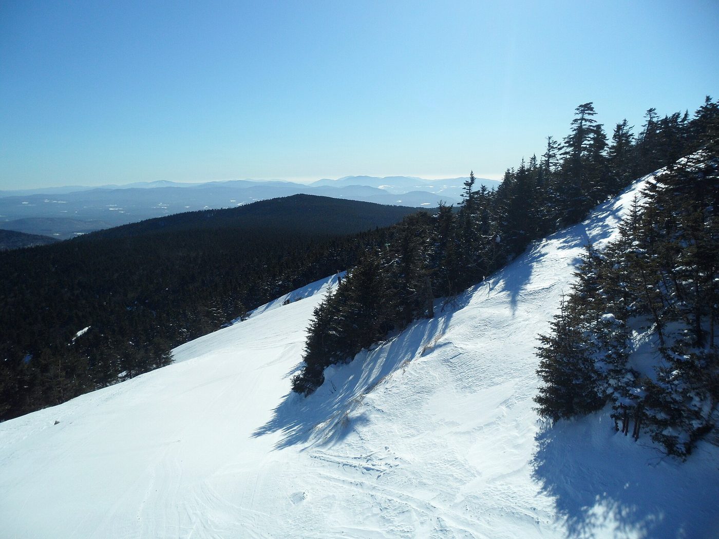 Skiers on a groomed trail at Killington, Vermont, with the Green Mountains beyond
