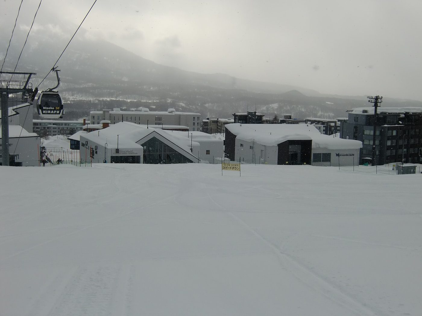 The Mountain Collective Pass reaches Japan through Niseko: the Hirafu gondola station and base buildings under heavy falling snow
