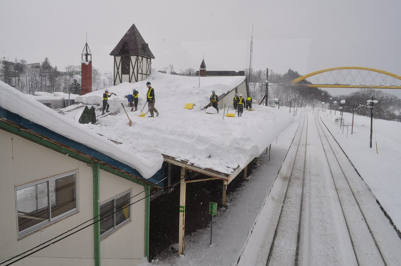 Railway staff shovelling deep snow off Niseko Station, the reality behind skiing in Japan
