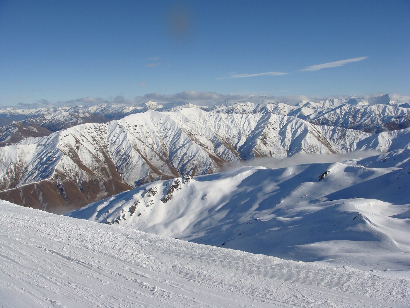 A groomed ski run above the jagged, snow-covered Southern Alps near Queenstown, New Zealand