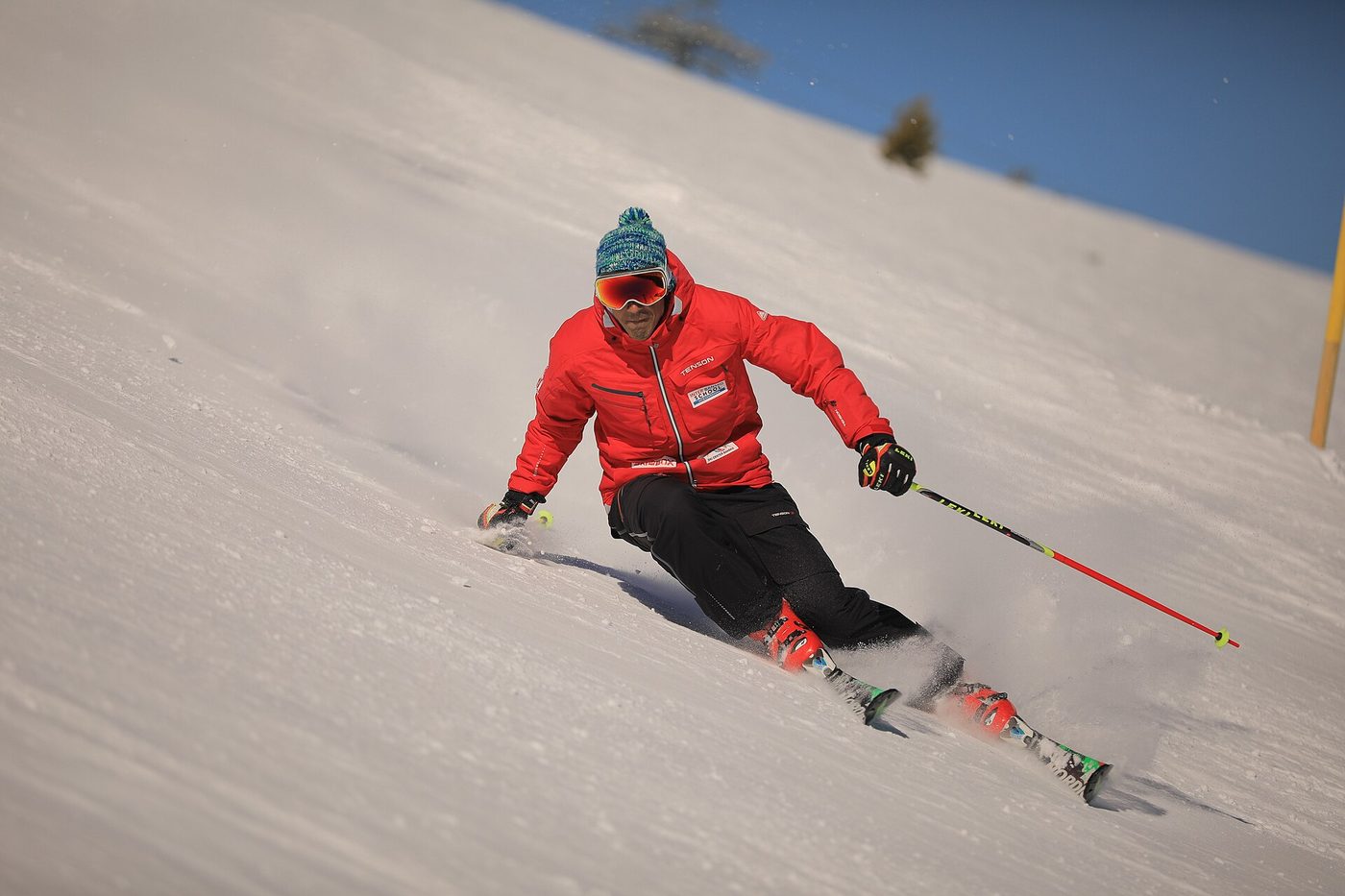 A ski instructor carving a clean turn on a groomed slope, showing how to get better at skiing