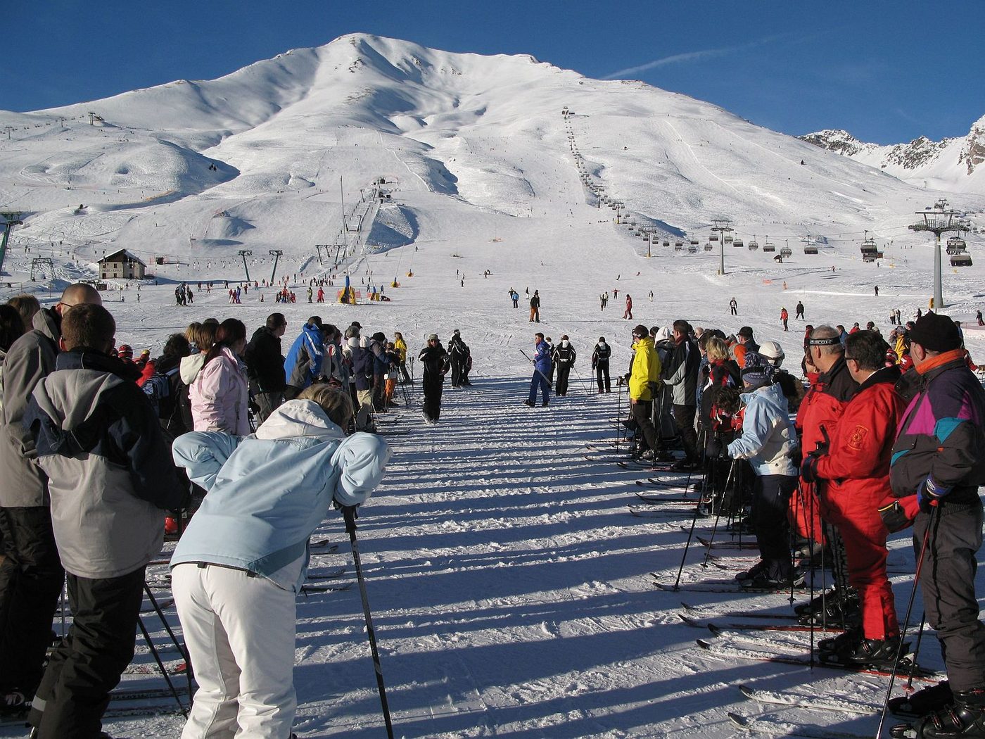 A crowd of adults gathering for ski school on a beginner slope at Passo Tonale, Italy