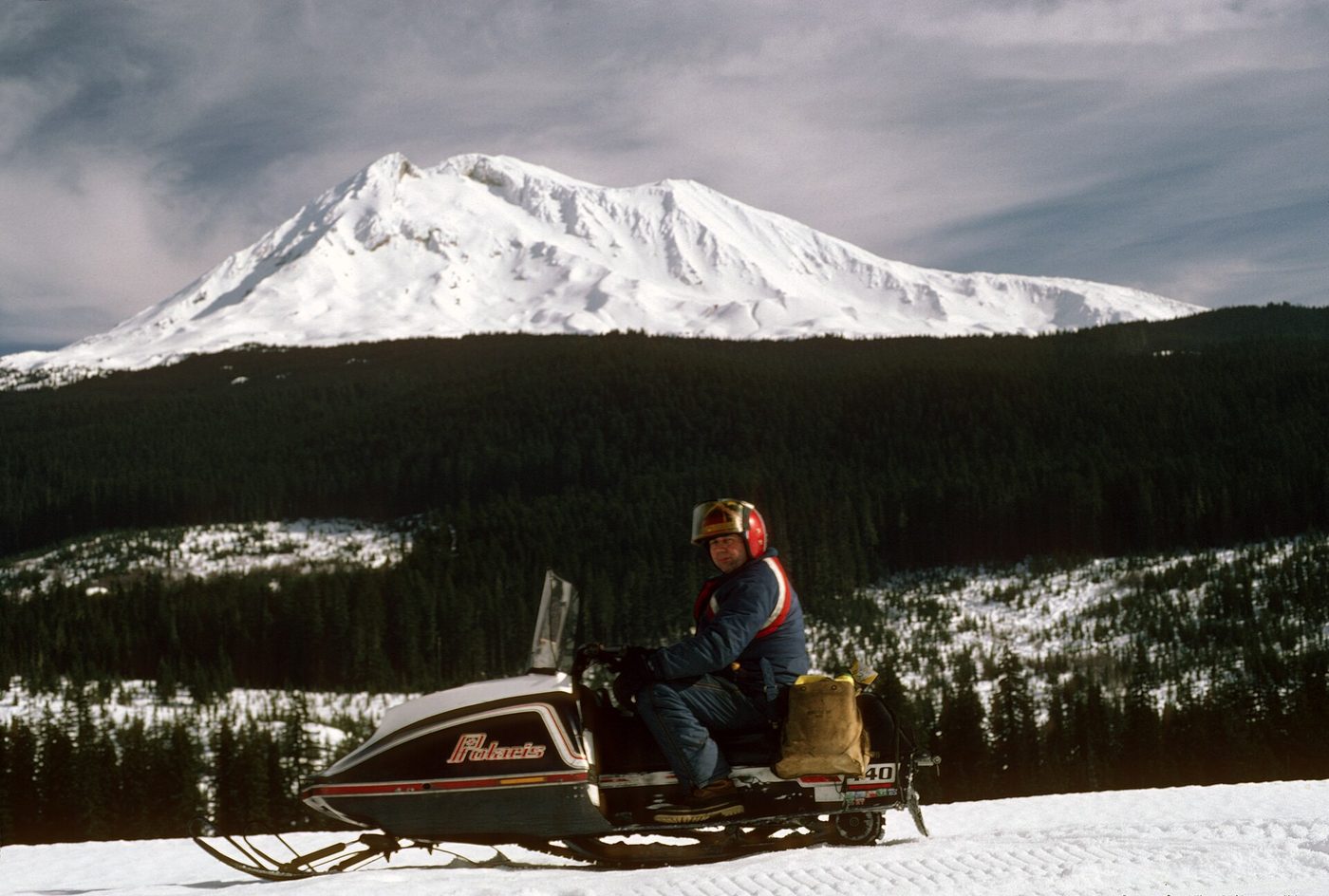 A snowmobiler on a snow-covered forest road below Mount Adams, Washington
