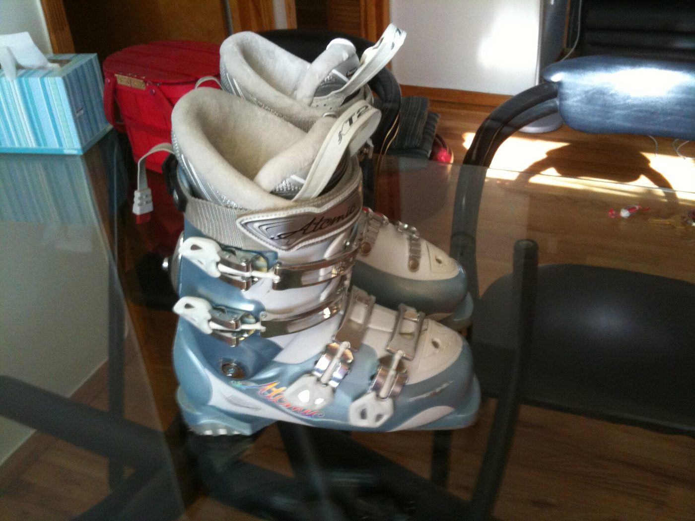 A pair of women's Atomic alpine ski boots, buckled and standing on a table at home