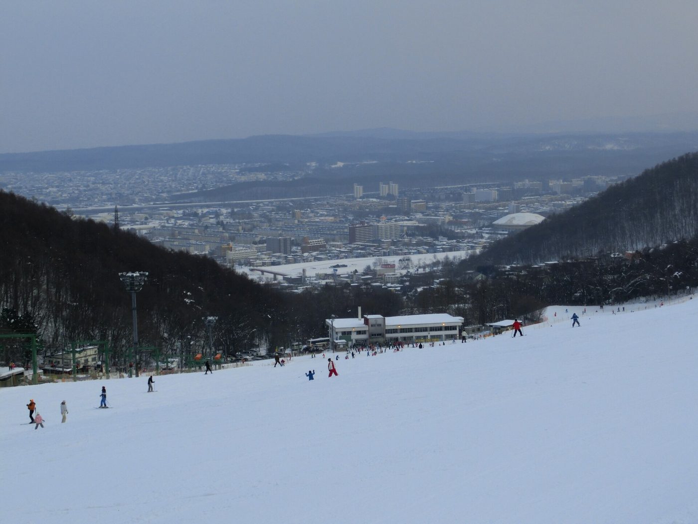 Families skiing a wide beginner slope at the Mt. Moiwa ski area above the city of Sapporo, Japan